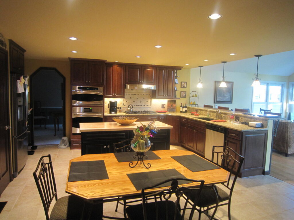 A custom kitchen remodel with dark cabinets, granite countertops, and a unique curved island by Hibbard Home Improvement in Williamsville, NY.