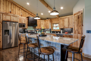A custom kitchen remodel featuring wooden cabinets, a large granite island, and stainless steel appliances by GCU Custom Builders in Louisville, KY.