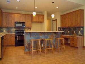 A custom home kitchen featuring wooden cabinets and a tiled breakfast bar by Aubrey Homes in Austin, TX