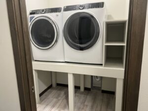 A custom-built laundry platform with integrated shelving for a washer and dryer by The Sioux Falls Handyman in Sioux Falls, SD.