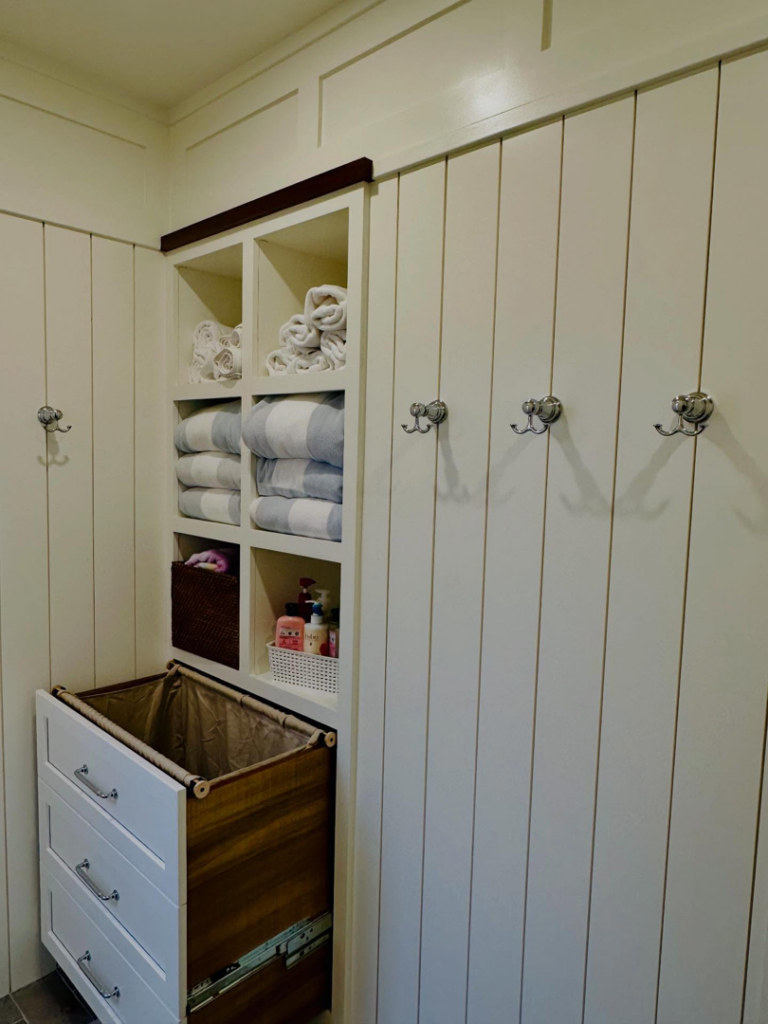 Custom laundry room or bathroom storage unit with shelves and a pull-out hamper by Lardieri's Custom Woodworking Company, Inc. in Lakewood, NJ.
