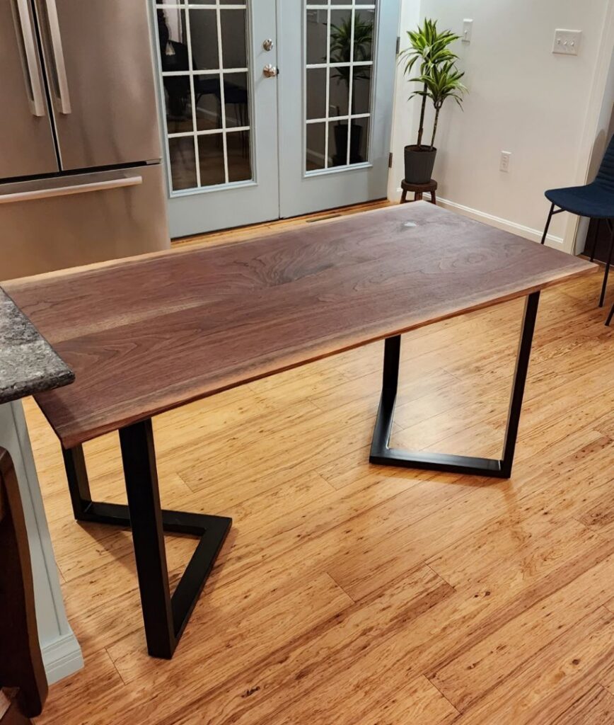 A custom-made live-edge wooden table with black metal legs, built and assembled by Dovetails Services LLC in Derry, NH.