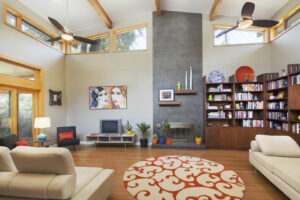 A custom-built living room with a vaulted ceiling, exposed beams, and a large fireplace by Transformations Custom Build in Austin, TX