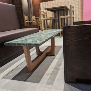 A custom-built coffee table with a green marble top and wooden base by Gilbert Designs Tulsa, OK.