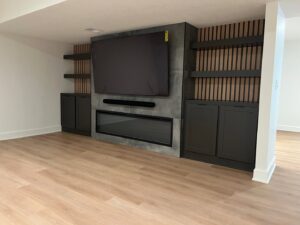 A custom-built media center with integrated TV, electric fireplace, and shelving by H4 Construction and Remodeling in Blue Springs, MO.