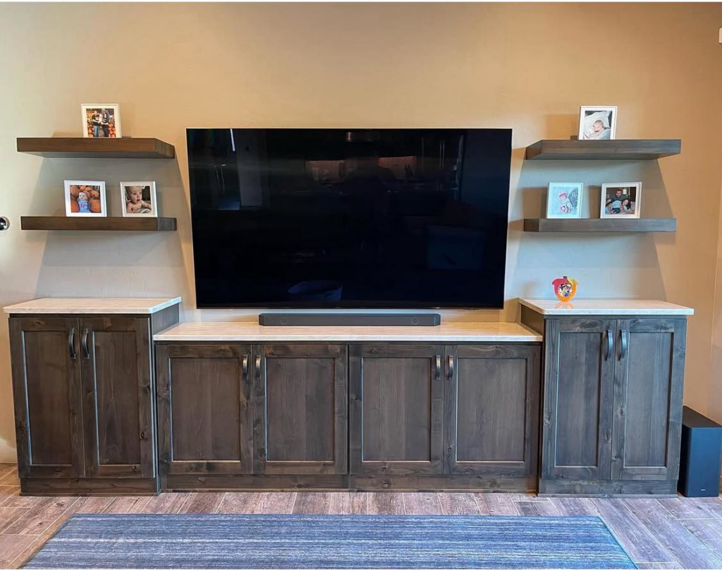 Custom media console installation with dark wood cabinets and floating shelves by Arizona Cabinet & Countertop Company in Tucson, AZ.