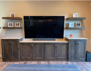 Custom media console installation with dark wood cabinets and floating shelves by Arizona Cabinet & Countertop Company in Tucson, AZ.
