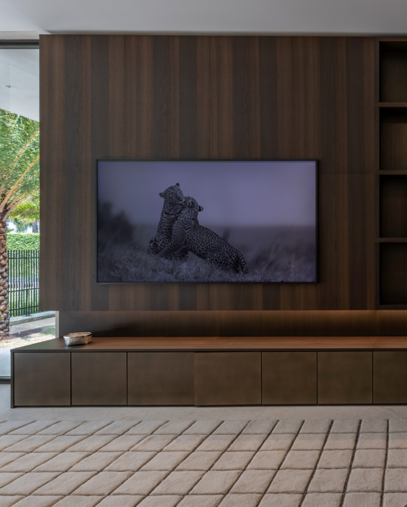 Custom media wall with integrated cabinetry and wood paneling by J Romano Group in Miami Beach, FL