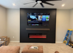 A newly installed custom media wall with a mounted TV and electric fireplace by Jason Roberts Painting and Remodeling in Louisville, KY.