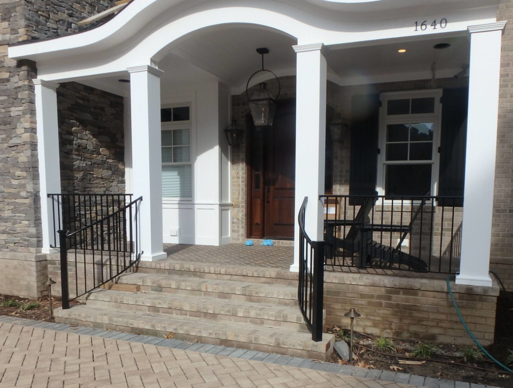 Custom metal railings installed on brick steps leading to a front porch by Custom Railing Solutions in Norfolk, VA