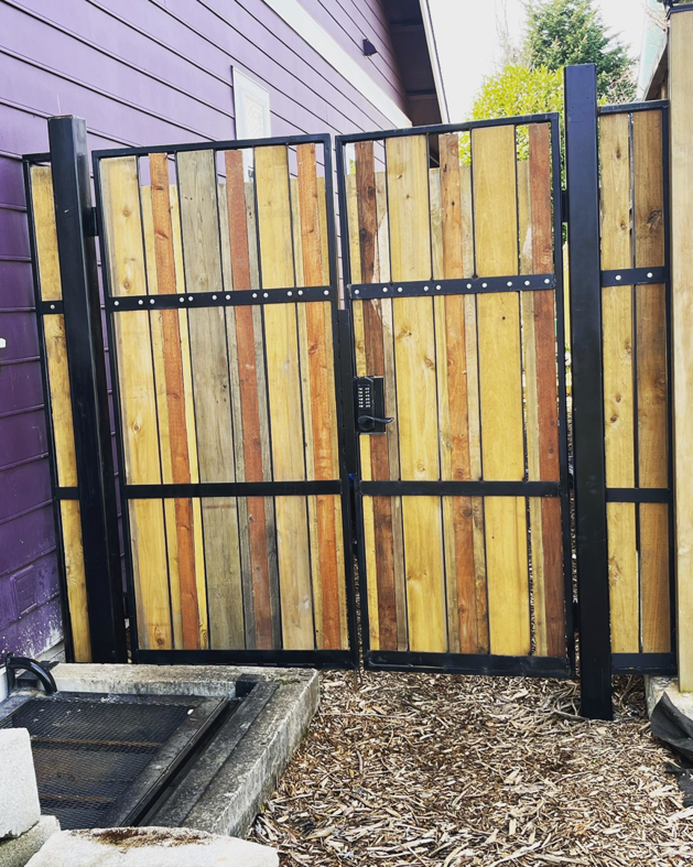 A newly installed custom metal and wood gate with a keypad lock by Loper & Slag metal fabrication design in Portland, OR.