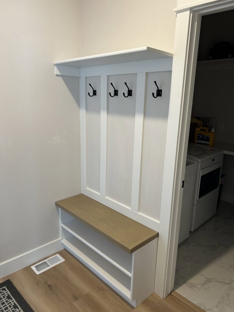 A custom-built mudroom bench with coat hooks and shoe storage by Rockin & Rollin Handyman Services in North Ogden, UT.
