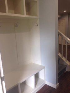 A custom-built white mudroom bench and storage unit with coat hooks by J Development in Pittsburgh, PA.