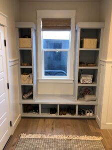 Custom built-in shelving and bench around a window in a mudroom, crafted by The Huckleberry Handyman in Meridian, ID.