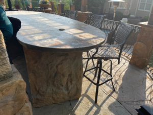 A custom-built outdoor bar and countertop with a stone base and seating by Burton Restoration LLC in Bend, OR.