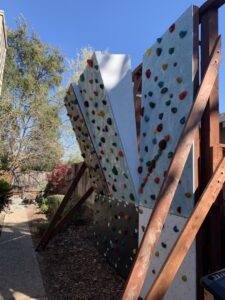 A custom-built outdoor climbing wall with colorful holds, a unique yard project by Dan's Home and Yard in Oakland, CA.