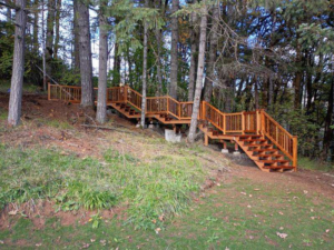 A custom-built outdoor wooden staircase winding through a wooded area by United Property Improvement in Eugene, OR.