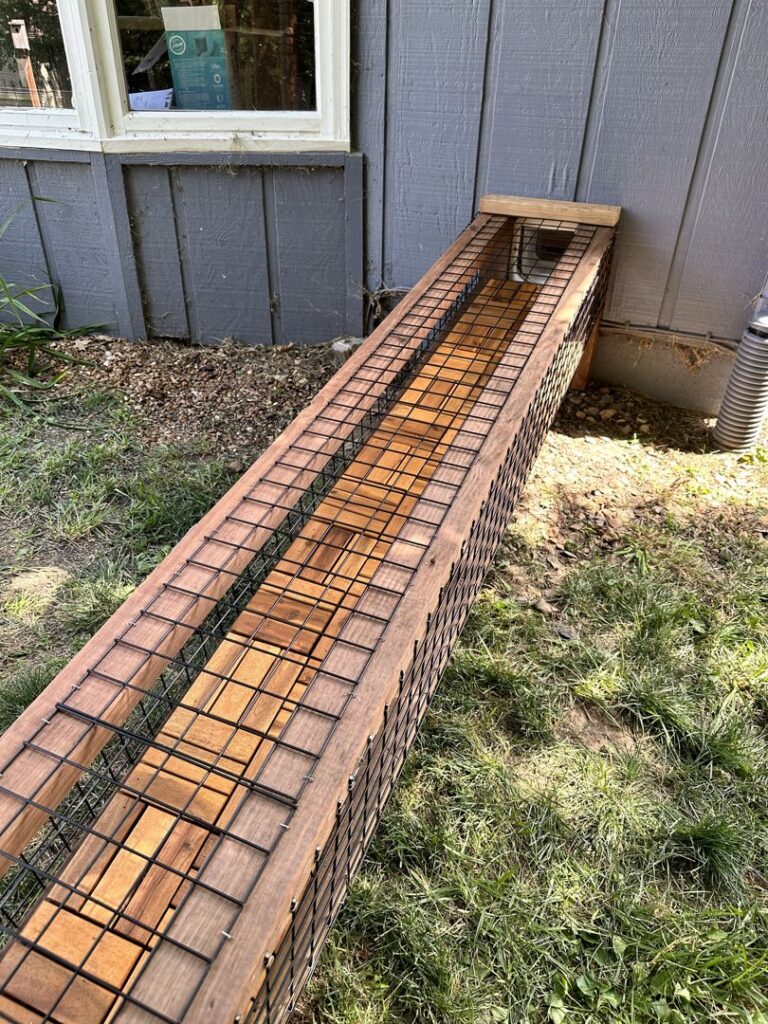 A custom-built long wooden structure with wire mesh, likely for a garden or outdoor space, created by Homefix Lawrence in Lawrence, KS.