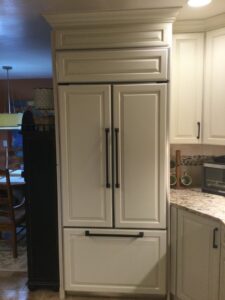 A kitchen with a custom paneled refrigerator and light-colored cabinets, a project by Cincinnati Cabinet Refacing in Cincinnati, OH.