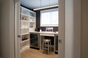 A custom pantry or bar area with built-in shelving, wine cooler, and a small desk installed by Closet Creations Inc. in Sleepy Hollow, NY.