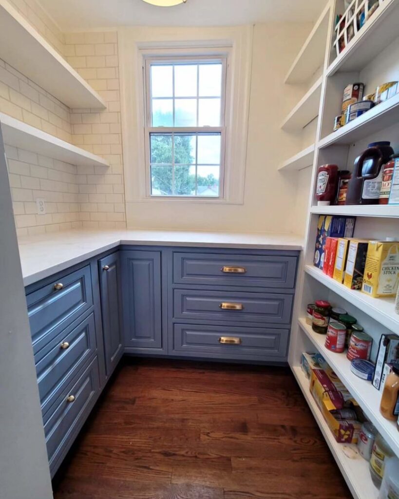 A custom pantry design featuring blue lower cabinets, white shelving, and subway tile backsplash by DeShong Design + Remodeling in Pittsburgh, PA.