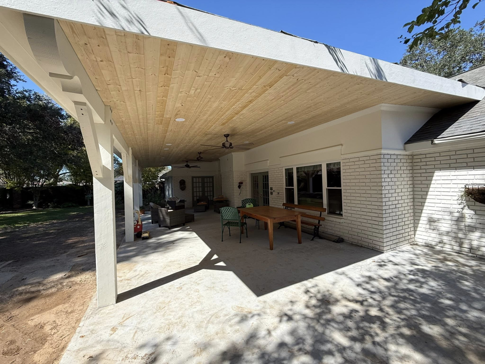A custom-built outdoor patio cover with a wooden ceiling and white columns by Acadian Carpentry LLC in Lafayette, LA.