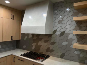 A finished kitchen featuring a custom plaster range hood and geometric tile backsplash by Plasters of Italy in Plano, TX