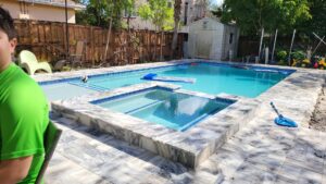 A custom-designed swimming pool and spa with a surrounding patio, completed by BAFCO POOLS in Hialeah, FL.