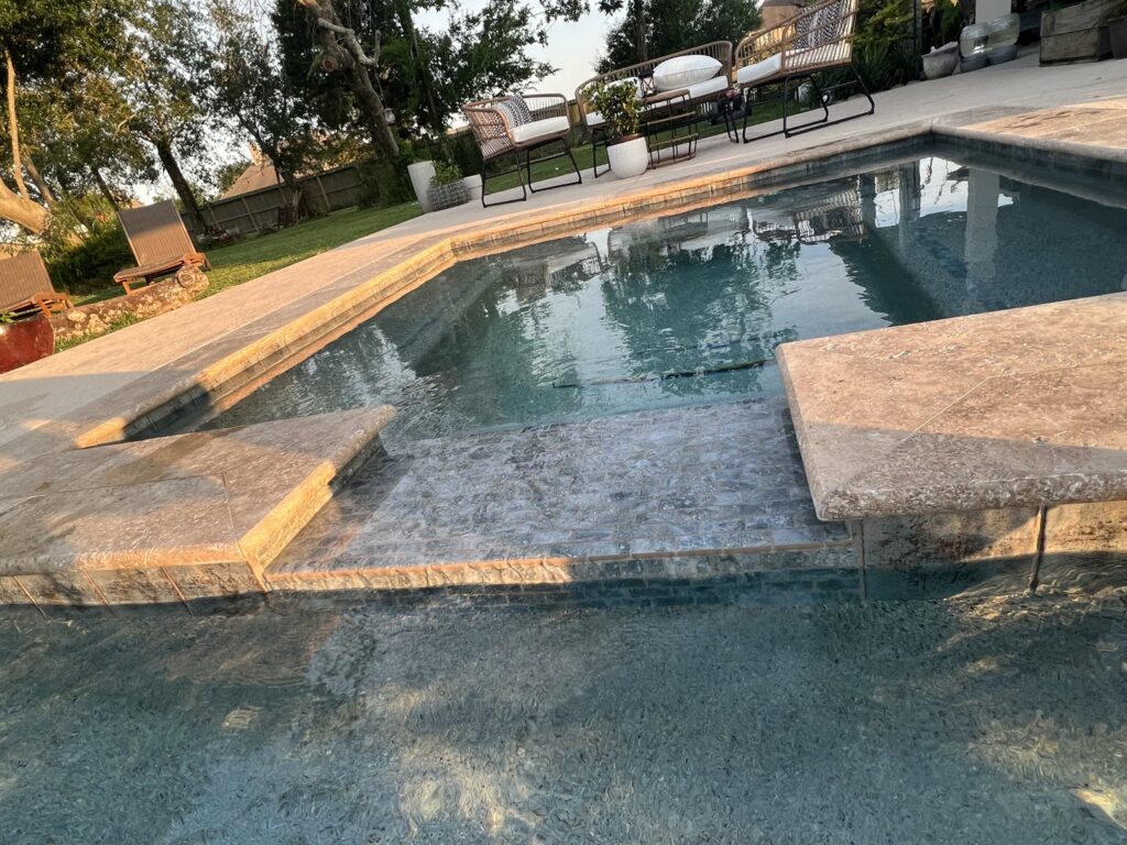 Custom pool steps featuring beautiful mosaic tiling, a detail from Limitless Custom Pools and Backyards in Houston, TX.