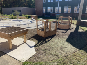 Custom-built raised garden beds with protective covers and picnic tables in an outdoor area by NARDI Construction, Inc. in Frederick, MD.