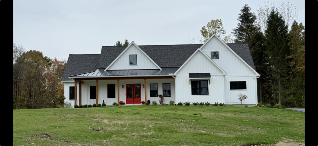 A custom-built ranch-style home with white siding, a dark roof, and red front doors by McDonald Custom Homes in Schenectady, NY.