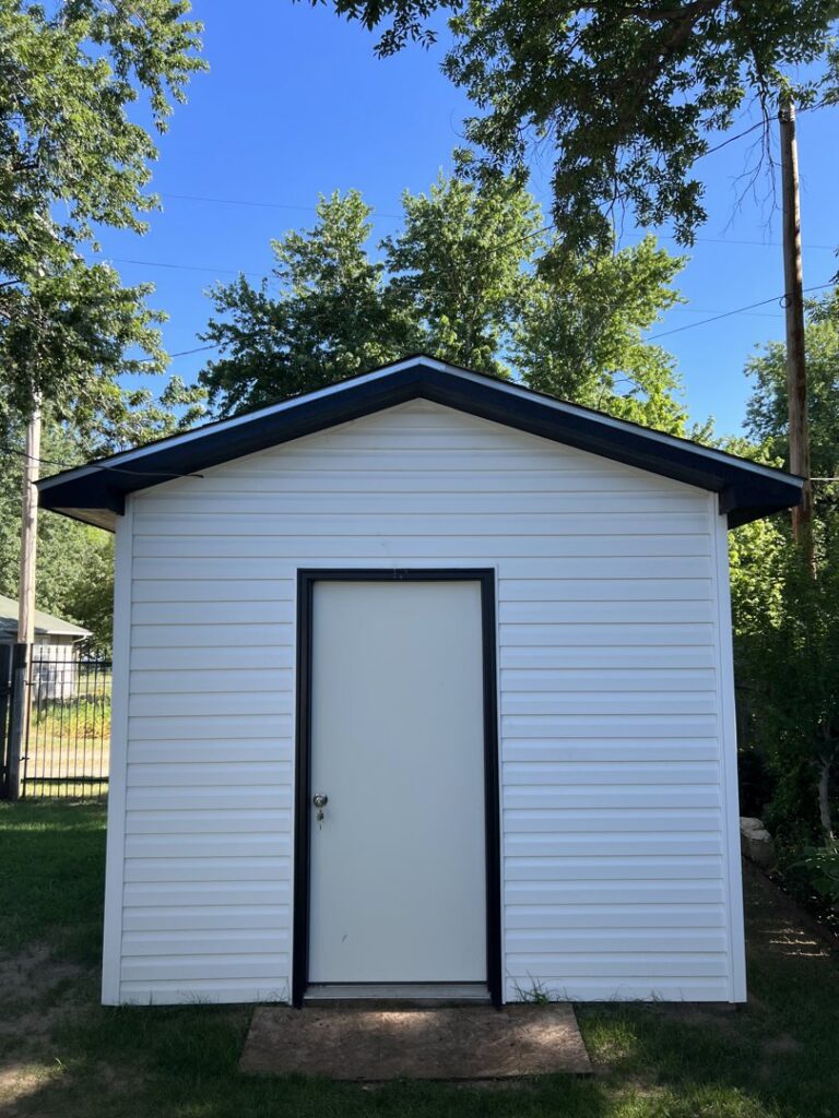 A newly constructed white shed with black trim by Smitty's Handyman Service LLC in Mesquite, TX.