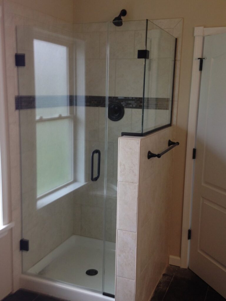 A custom shower featuring light tiles and a functional half-wall, part of a bathroom renovation by Lehigh Shower Glass in Bethlehem, PA