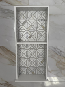 A custom built-in shower niche with intricate decorative tile work by River Oak Renovations in Augusta, GA.