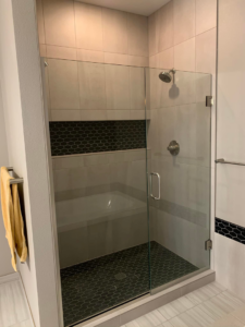 A custom shower with a built-in bench and dark hexagonal floor tiles by Andalex Construction LLC in Gresham, OR.