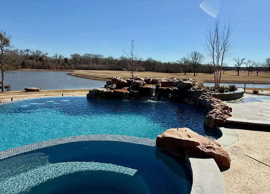 Custom spa and rock waterfall feature of a pool project by First Class Pools & Spas in Sachse, TX.