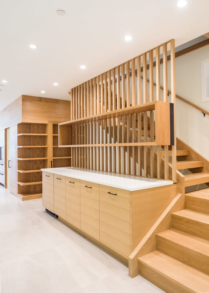 A custom wooden staircase with a slatted room divider and built-in cabinetry by S.N. Peck Builder, Inc. in Chicago, IL.