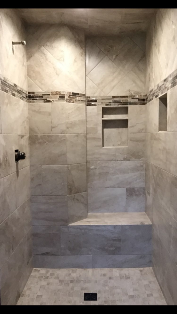 A custom tiled shower featuring a built-in bench and multiple storage niches by Fueled Up Flooring- Justin Watruba in Eau Claire, WI.