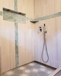A custom tiled shower design with decorative accent strips and hexagonal floor tiles by Ace Tile & Finishing LLC, your general contractor in Philadelphia, PA.