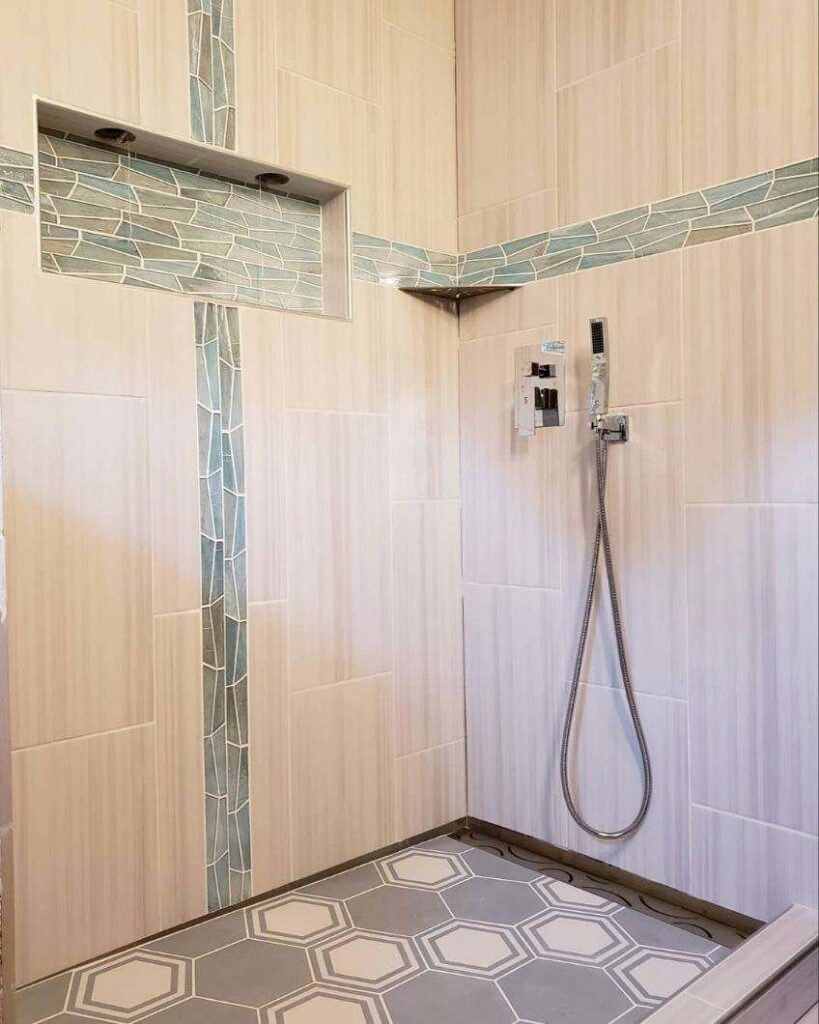 A custom tiled shower design with decorative accent strips and hexagonal floor tiles by Ace Tile & Finishing LLC, your general contractor in Philadelphia, PA.