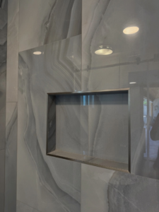 A custom-built tiled shower niche with sleek grey tiles, a detail from a bathroom remodel by AGM Remodeling LLC in Scottsdale, AZ.
