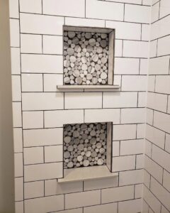 Custom tiled shower wall with two recessed niches featuring decorative pebble-look accent tiles by Ace Tile & Finishing LLC in Philadelphia, PA.