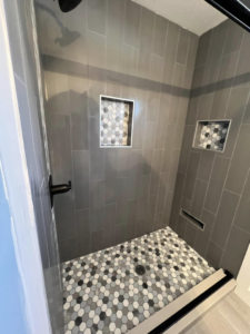 Custom tiled shower with built-in niches and hexagonal floor tiles by Roempagel Renovations LLC in South Bend, IN.