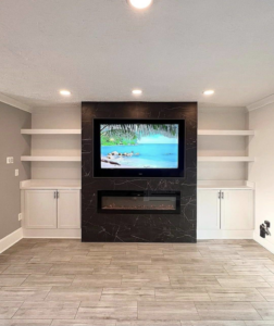 A custom TV wall with an electric fireplace and built-in shelving installed by Done Right Construction in Johnston, IA.