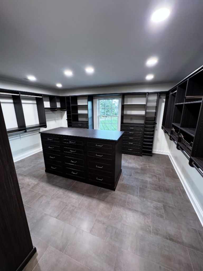 A large custom walk-in closet with dark cabinetry and a central island installed by Shipe Builders in Salisbury, MD.