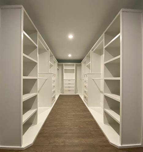 A custom-built walk-in closet with white shelving and drawers installed by Colorado ProBuilt in Aurora, CO