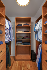 A custom-built walk-in closet with wooden shelving and drawers by EdgeWork Design Build in Minneapolis, MN.