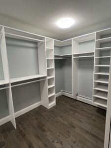 Custom white shelving and hanging rods installed in an empty walk-in closet by CWS Handyman LLC in Seekonk, MA