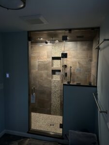 Custom walk-in shower installation with dark tile and pebble accents completed by Byrd's Contracting, LLC in Bristol, CT.