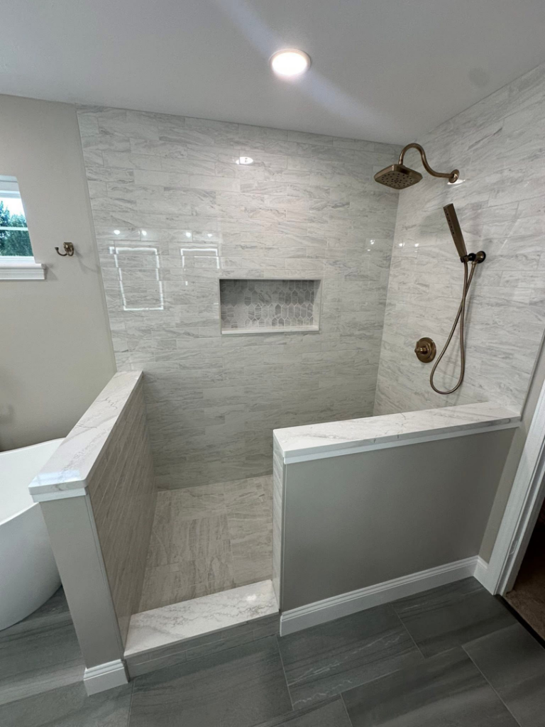 A custom walk-in shower with a decorative tile niche and modern fixtures by Quality Work Home Services in Syracuse, NY.
